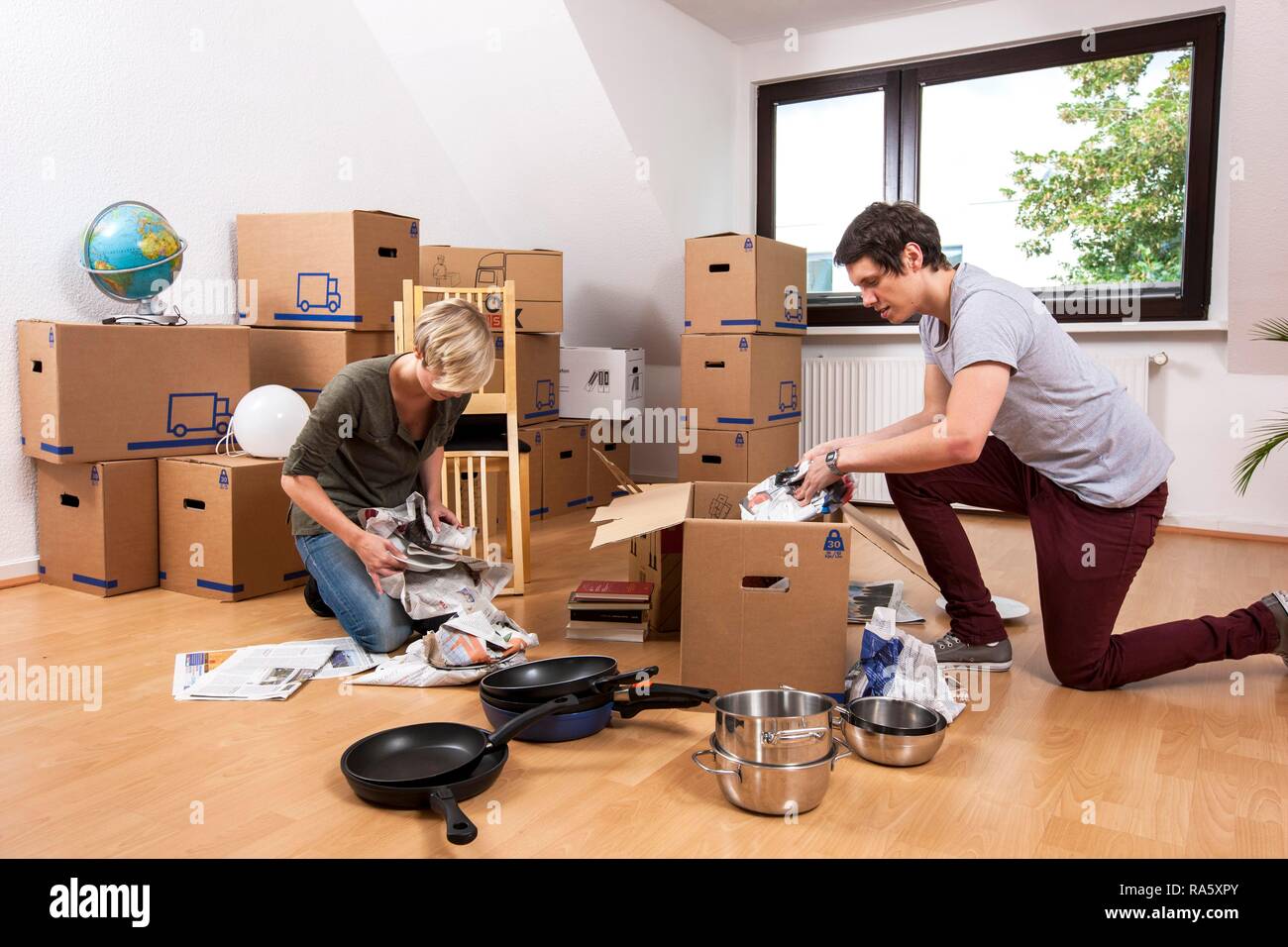 Junges Paar in einen leeren Raum in eine neue Wohnung Auspacken der ersten Boxen Stockfoto