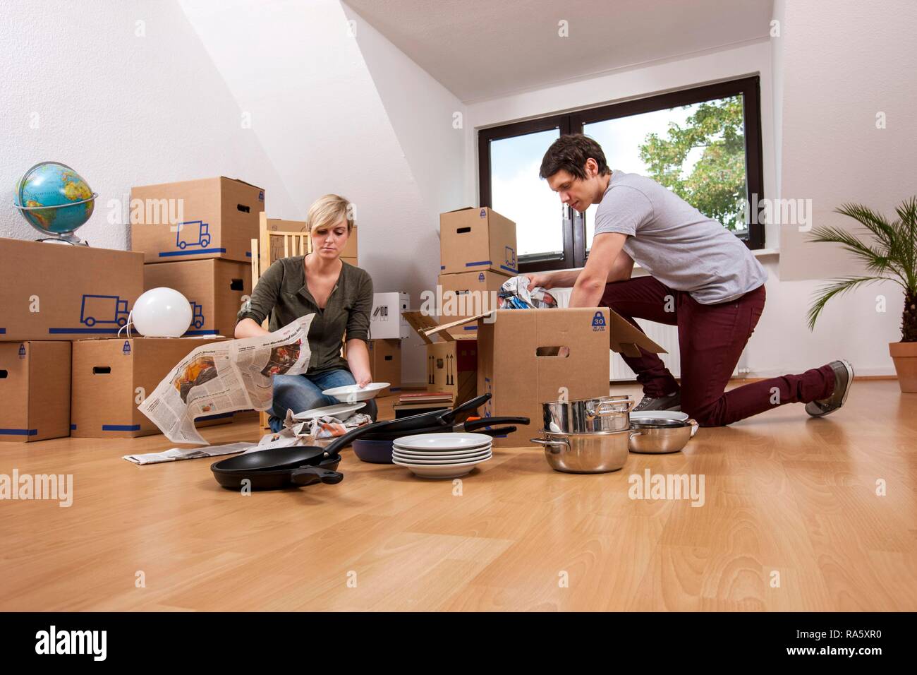 Junges Paar in einen leeren Raum in eine neue Wohnung Auspacken der ersten Boxen Stockfoto