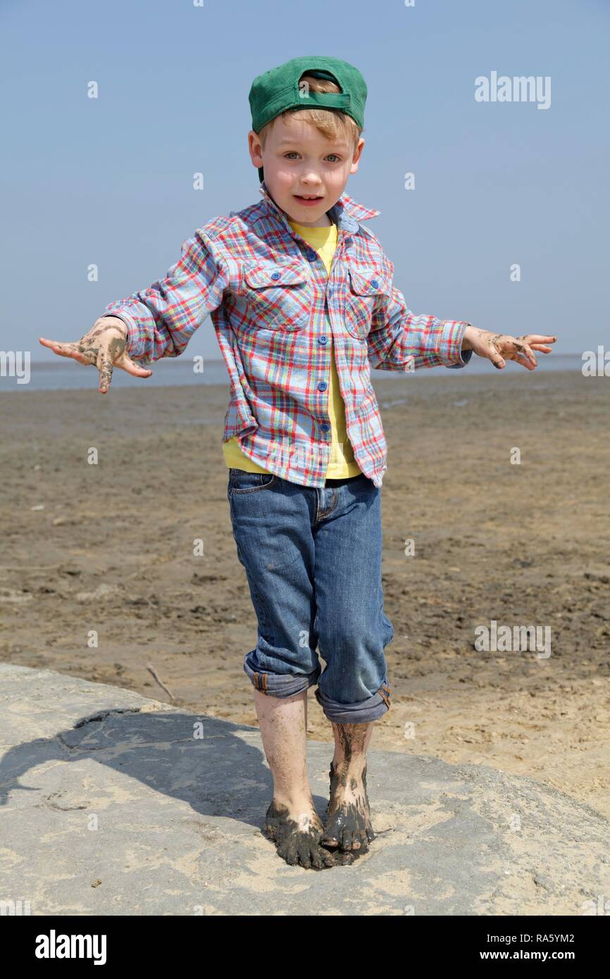 Junge mit Händen und Füßen voller Schlamm im Wattenmeer das Wattenmeer, Duhnen, Cuxhaven, Niedersachsen, Deutschland Stockfoto