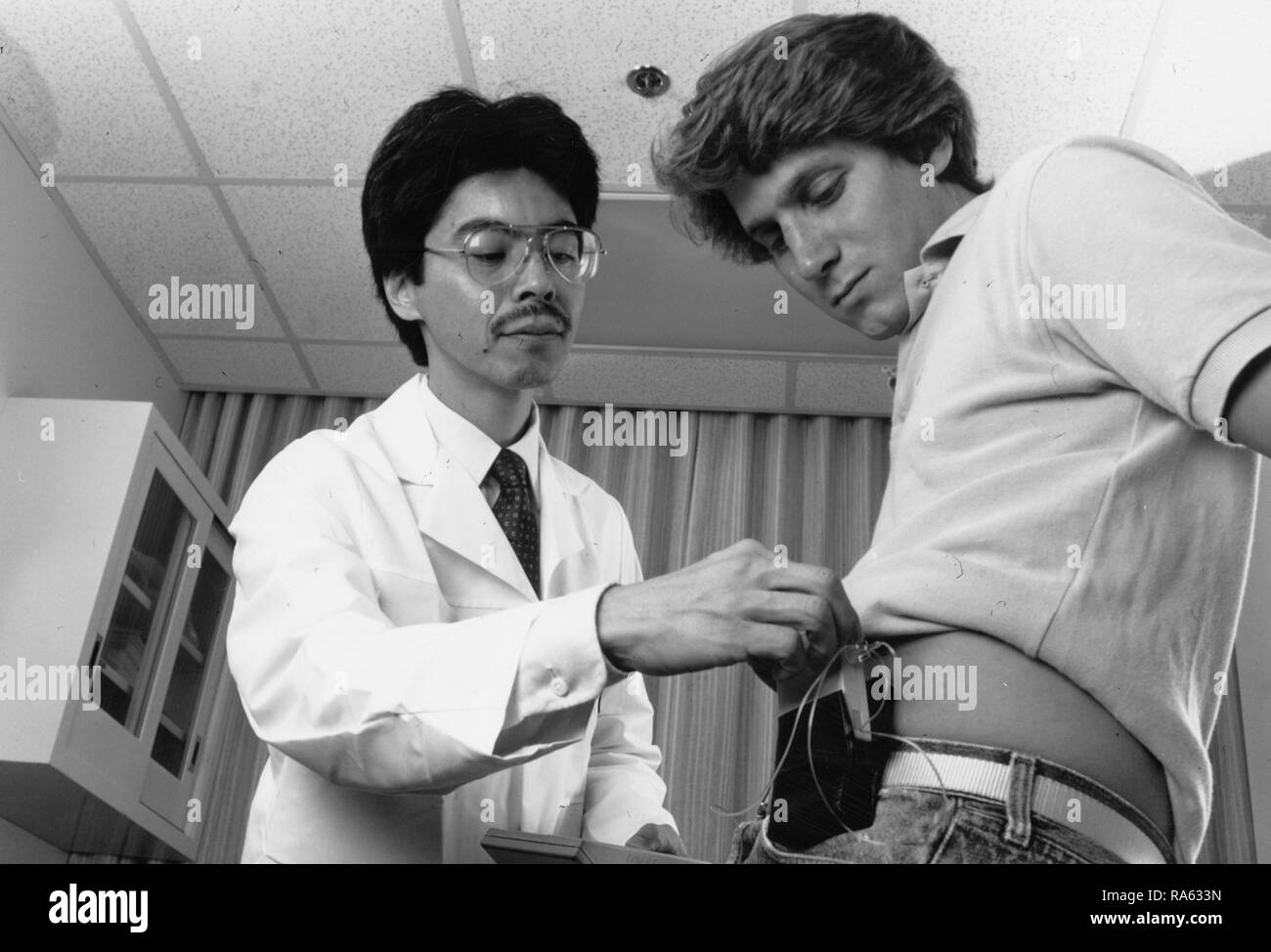 Ein Arzt beauftragt ein Patient in der Verwendung einer Insulinpumpe Ca. 1987 Stockfoto