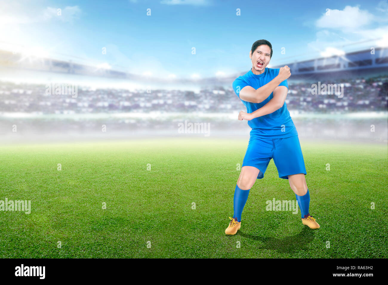 Schönen asiatischen Fußball-Spieler in der blauen Uniform feiert Sieg am Stadion Hintergrund Stockfoto