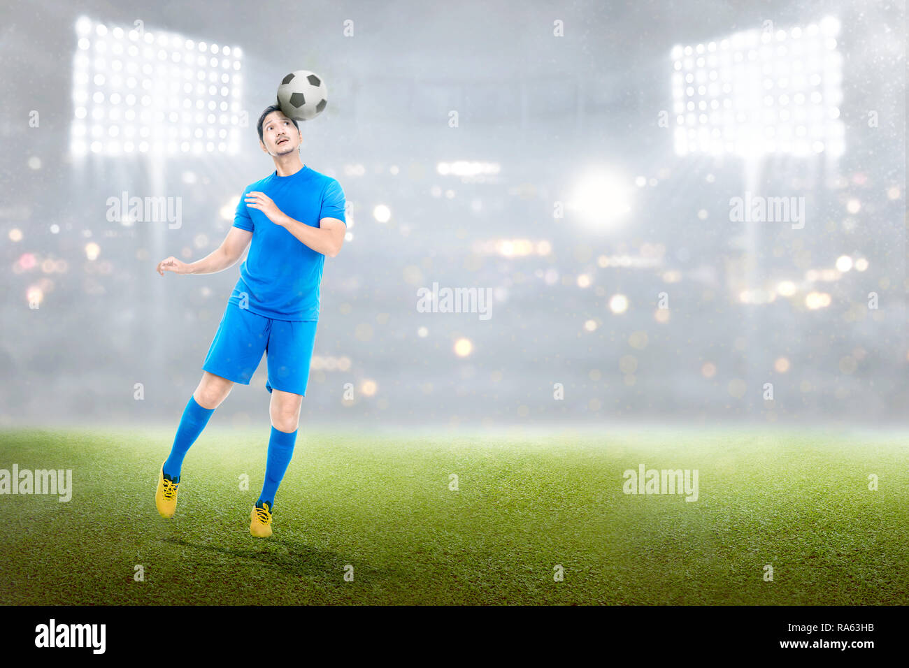 Attraktiven asiatischen Fußball-Spieler in Aktion mit der Kugel im Stadion Hintergrund Stockfoto