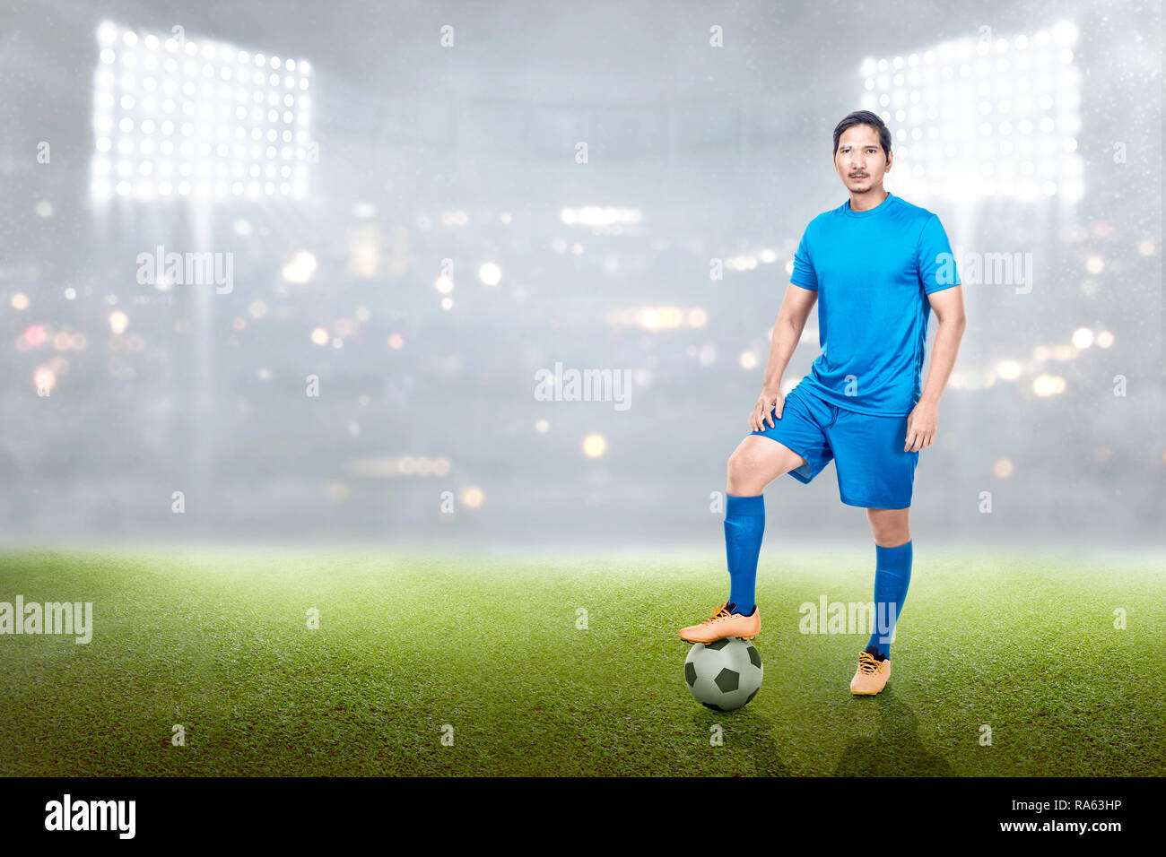Professionelle asiatischen Fußball-Spieler Mann stand mit Kugel auf seinem Bein im Stadion Feld Stockfoto