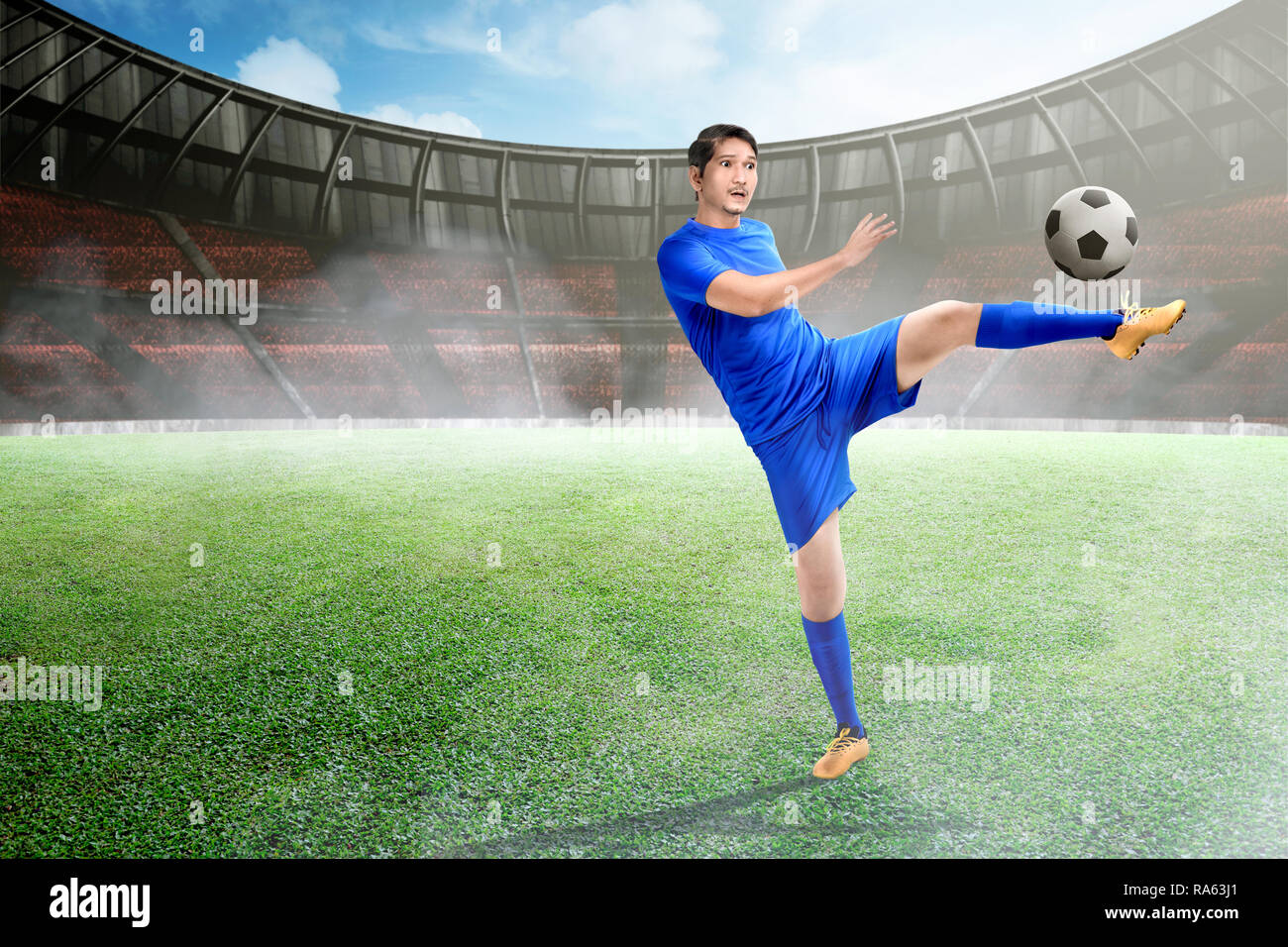 Attraktiven asiatischen Fußball-Spieler kicken den Ball in das Stadion Stockfoto