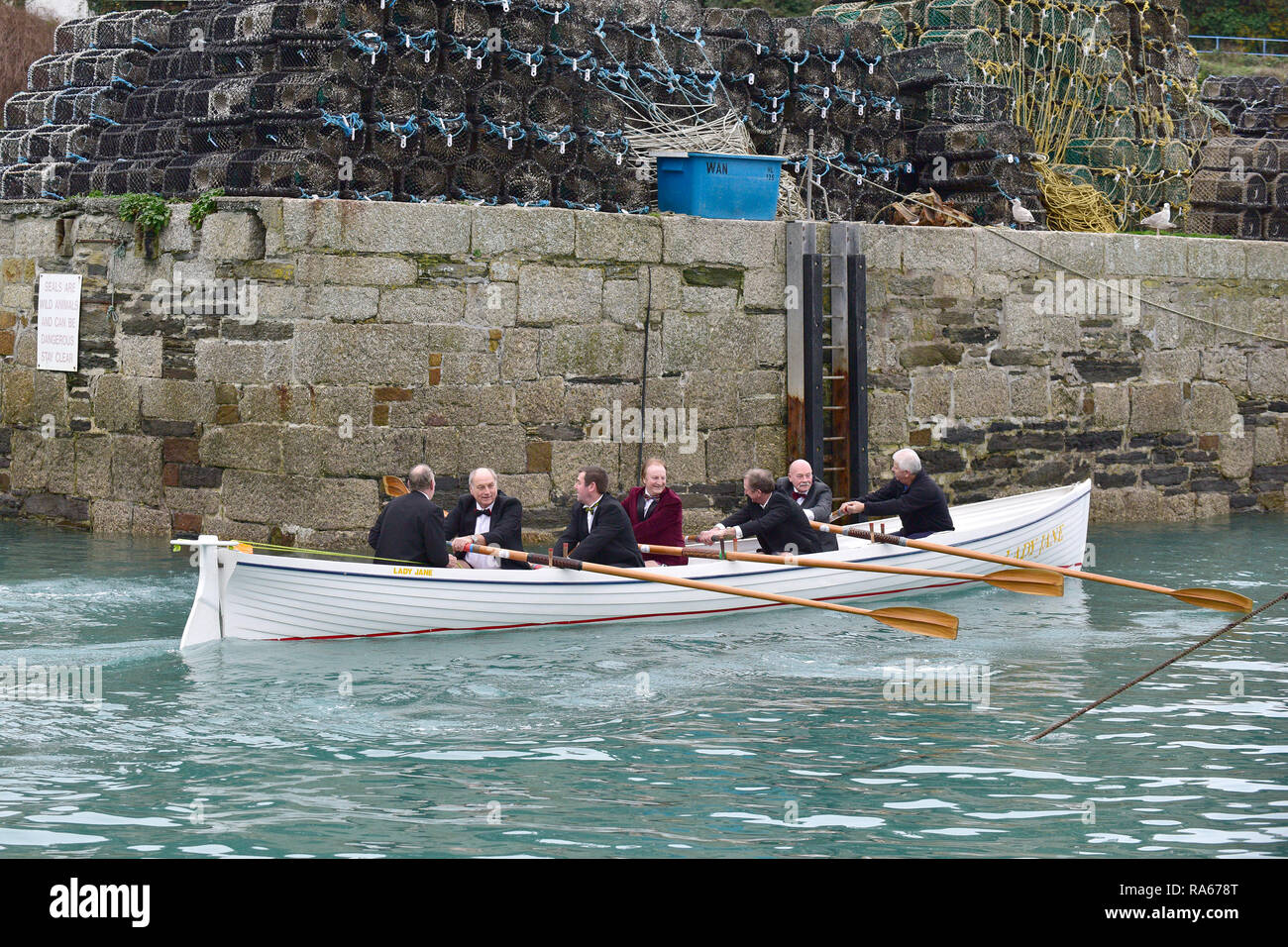 Newquay, Cornwall, England. 21. April 2018. Ältere Mitglieder von Newquay Ruderclub tragen Smokings aus auf ihrer jährlichen â € "Port Runâ €™ eingestellt. Eine Flasche Portwein ist Ruderte über Newquay Bay Porth Insel durch diese Ruderer in einem traditionellen Kornisch Pilot Gig. Sobald Sie den Boden der Flasche wird durch die Ruderer, die dann zu Newquay Hafen verbraucht. Gordon Scammell/Alamy Leben Nachrichten. Stockfoto