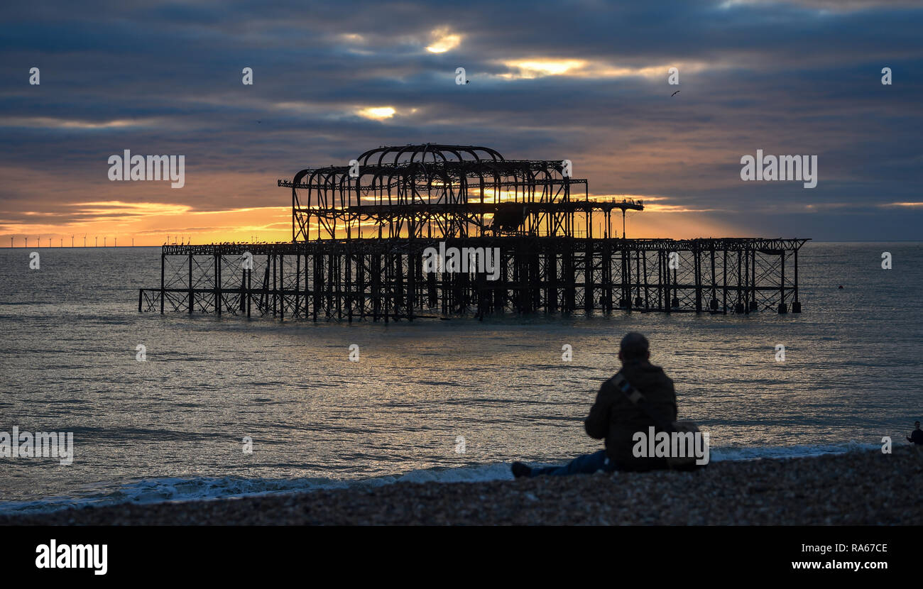 Brighton UK 1. Januar 2019 - ein Besucher beobachtet, wie die Sonne hinter der West Pier in Brighton am Ende des schönen Nachmittag an der Südküste von Großbritannien: Simon Dack/Alamy leben Nachrichten Stockfoto