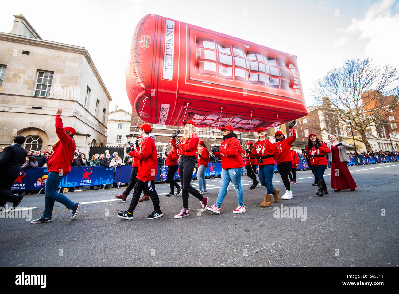 Riesige rote Telefonzelle Ballon am Tag der Londoner New Year's Parade 2019, UK. Ballon handler Robert E Fitch High School Chamber Choir Festival Chorus von Connecticut, USA Stockfoto