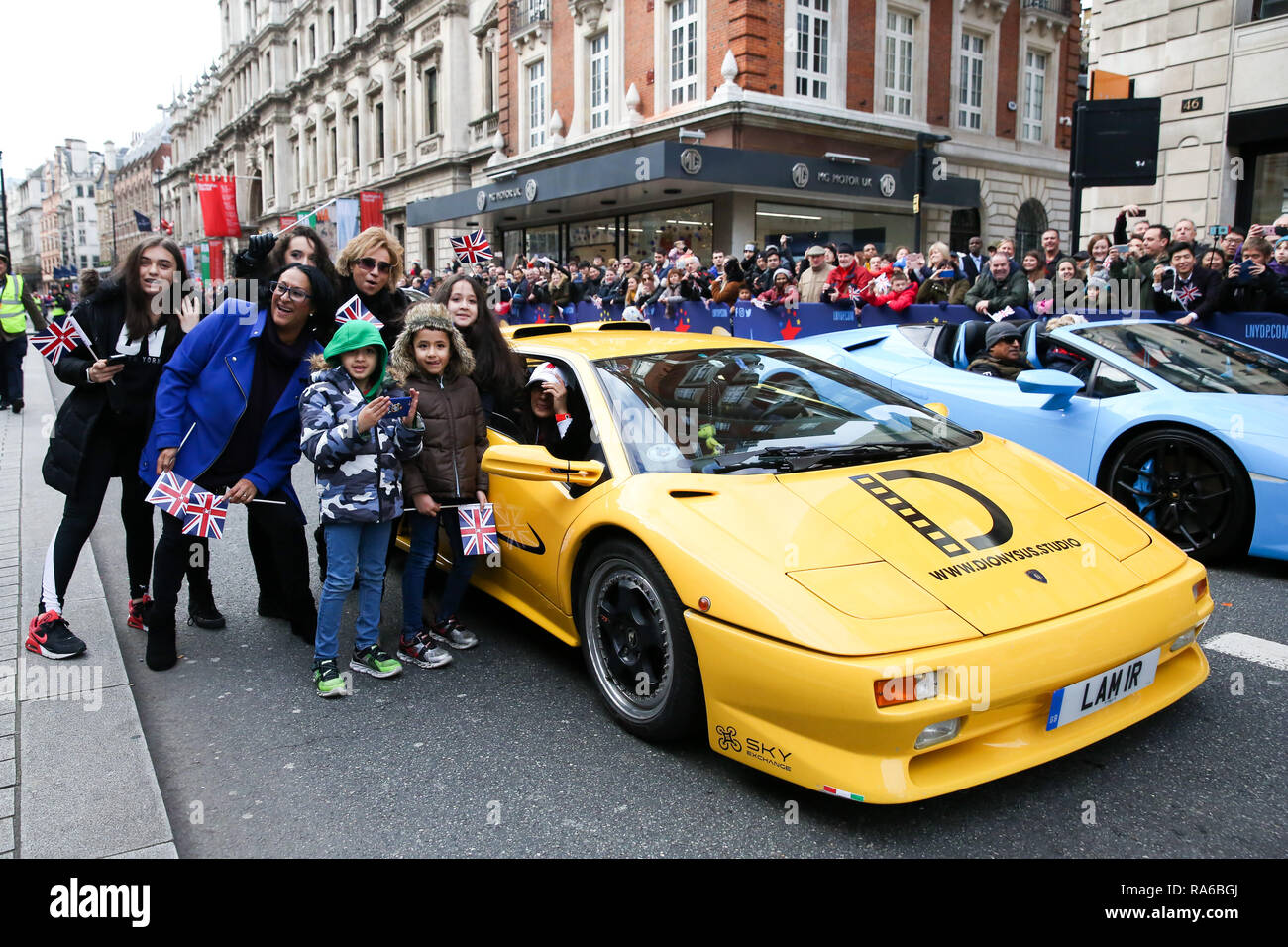 Menschen gesehen Neben einem Lamborghini während der Parade. Über eine halbe Million Zuschauer gesäumt, die 2,2 km Route von Piccadilly Circus, dem Parlament Square als Mehr als 8.000 Künstler aus 26 Ländern in Day Parade des 33. London des Neuen Jahres teilgenommen. Stockfoto