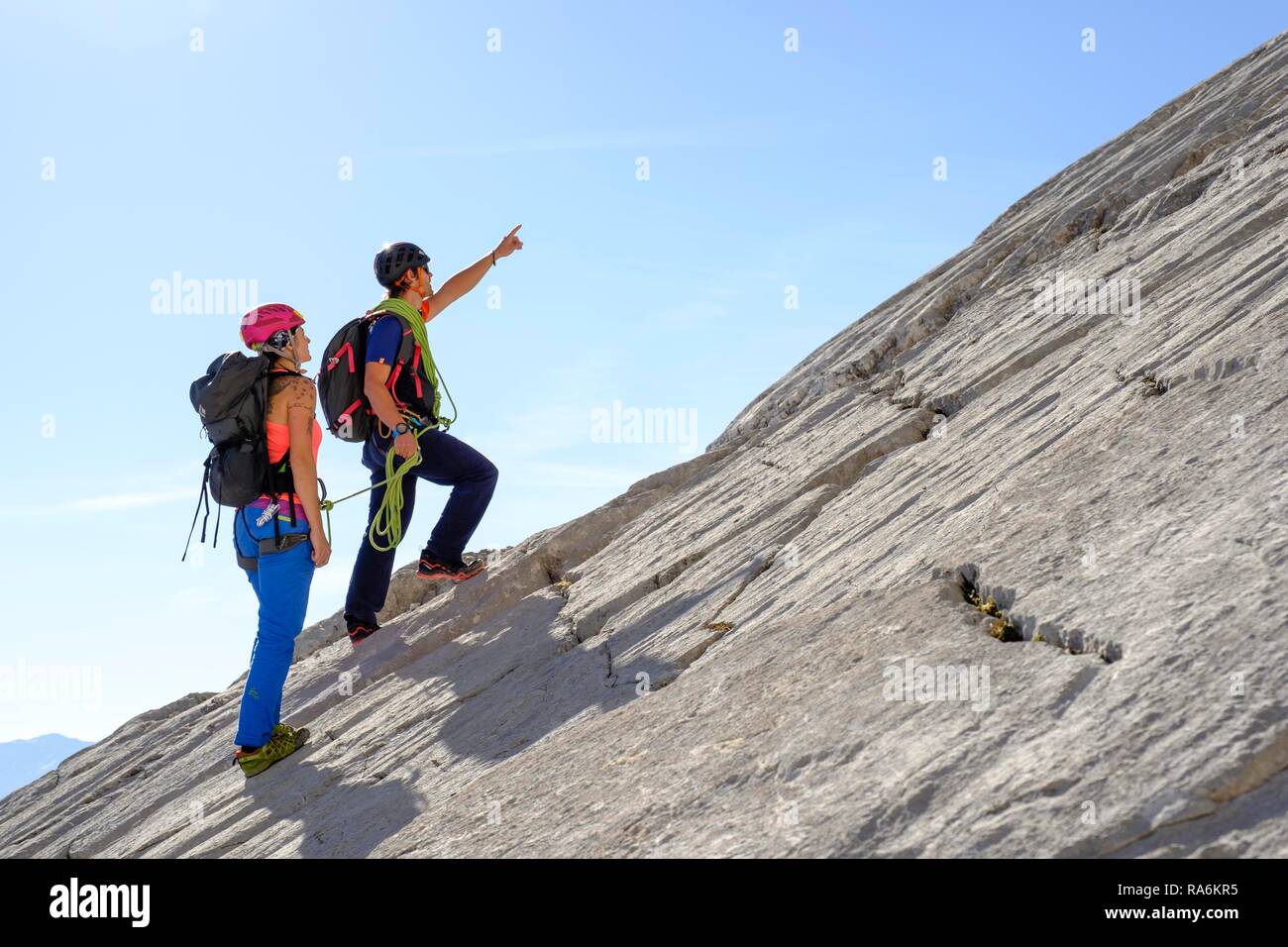 Bergführer führt eine junge Frau auf einem kurzen Seil durch eine Felswand, Wiederroute, Watzmann, Schönau am Königssee Stockfoto