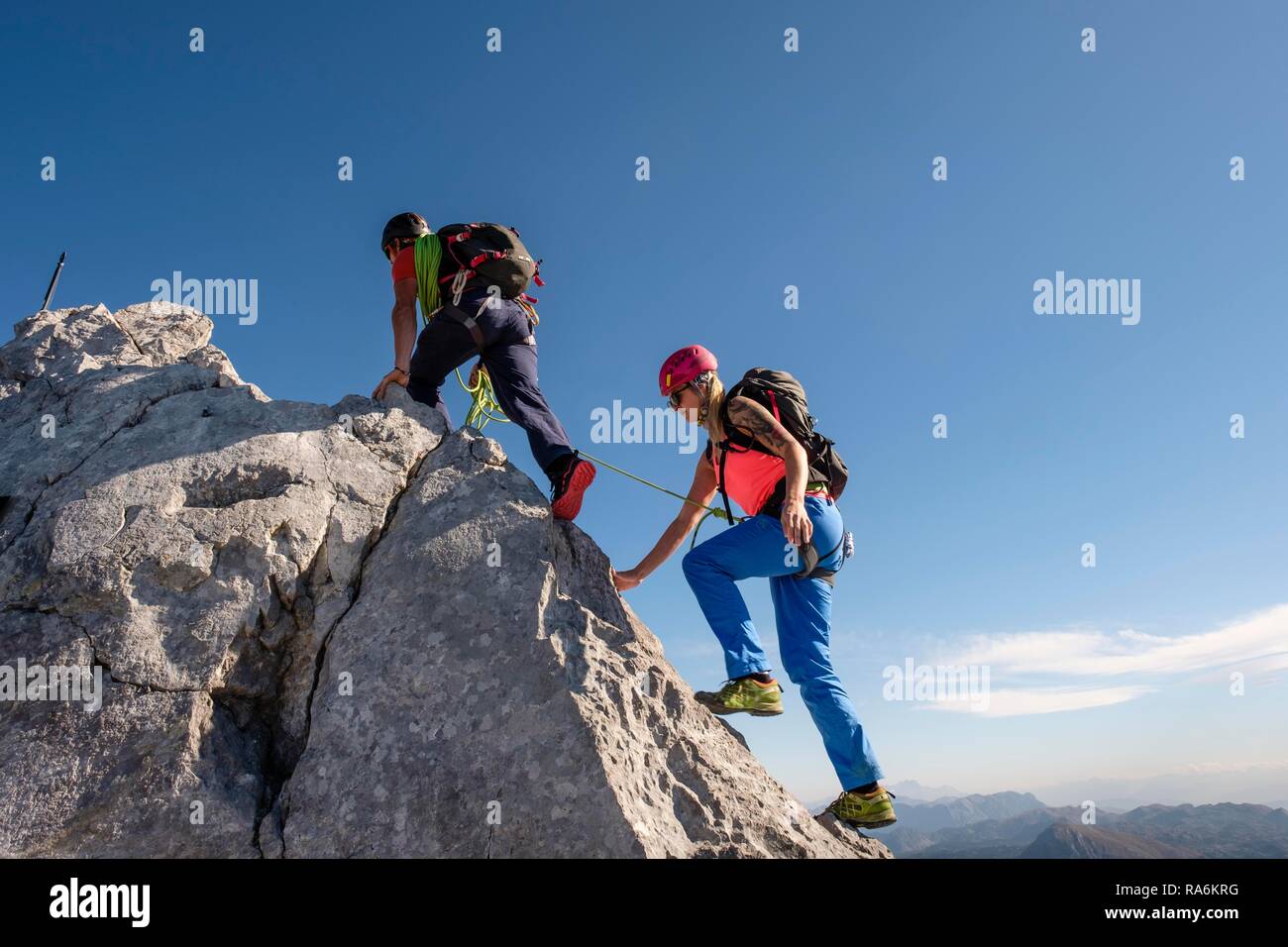 Bergführer führt eine junge Frau auf einem kurzen Seil durch eine Felswand, Wiederroute, Watzmann, Schönau am Königssee Stockfoto