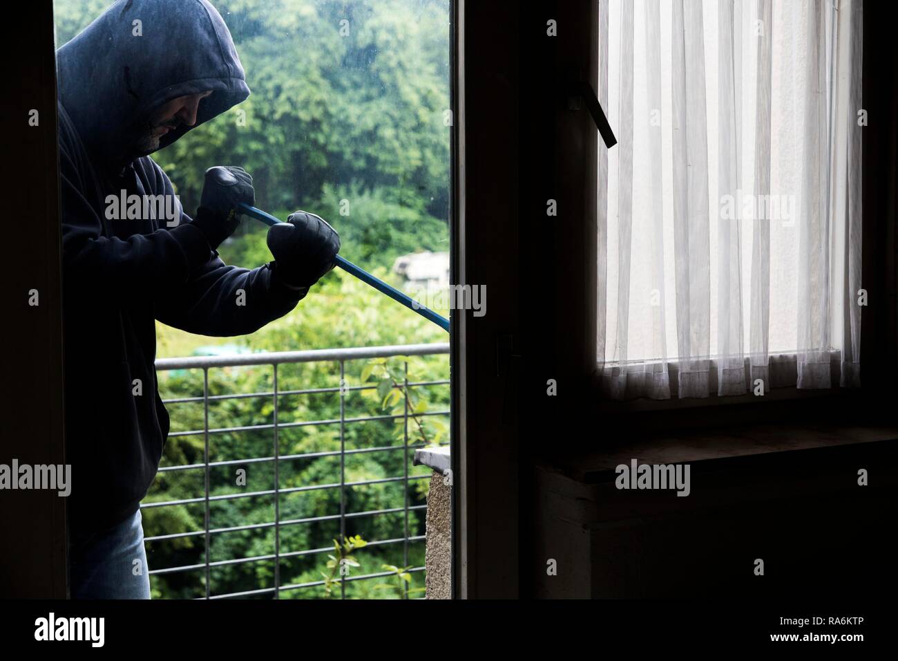 Symbol Bild von Einbruch, Täter versucht, in eine Wohnung zu brechen, nimmt ein Fenster mit einem Werkzeug, Deutschland Stockfoto