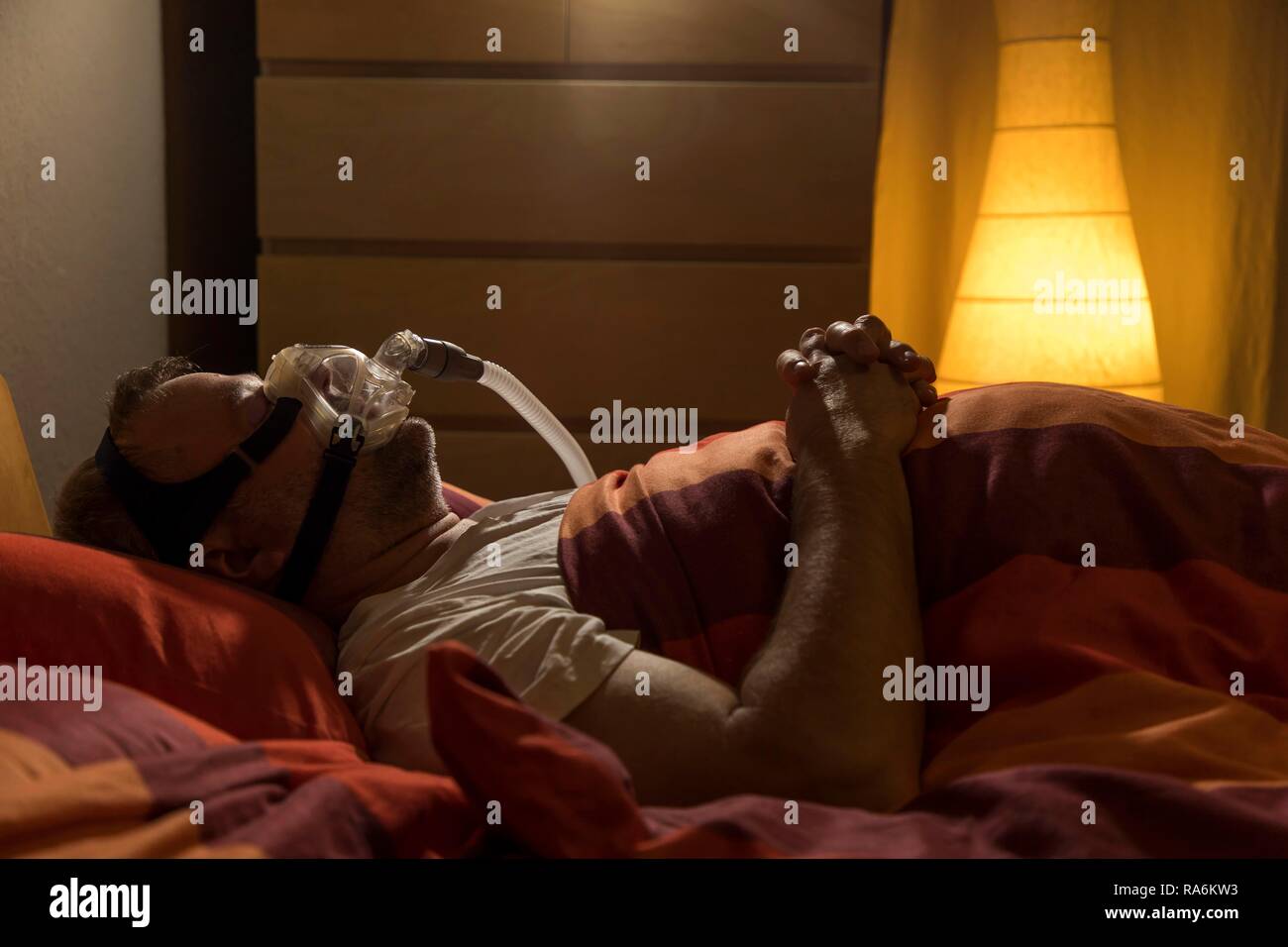 Menschen mit Schlafapnoe Syndrom, trägt eine CPAP-Maske beim Schlafen, Atemmaske, die Luft in die Atemwege drückt durch Stockfoto