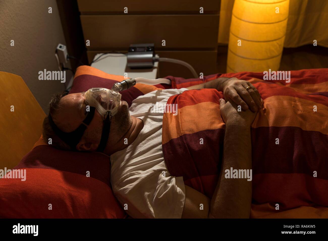 Menschen mit Schlafapnoe Syndrom, trägt eine CPAP-Maske beim Schlafen, Atemmaske, die Luft in die Atemwege drückt durch Stockfoto