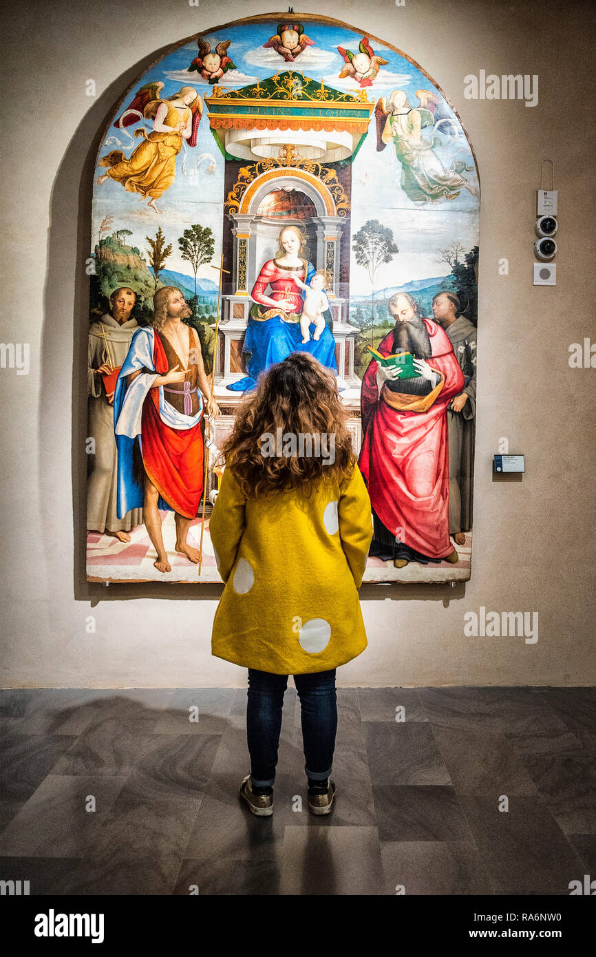 Nationalgalerie von Umbrien, Perugia, Umbrien, Italien. Ein Mädchen mit einem gelben Mantel von den Schultern bewundert ein riesiges Bild. Stockfoto