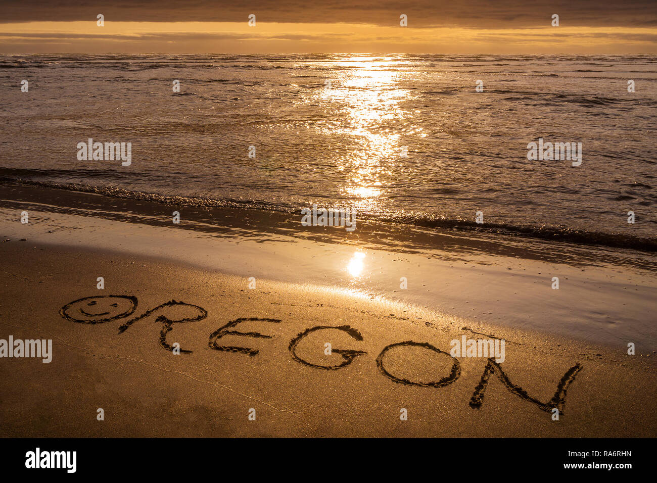 Oregon Sonnenuntergang. Oregon Text am Strand mit Sonnenlicht geschrieben Trails auf dem Ozean. Oregon Coast Konzepte. Stockfoto