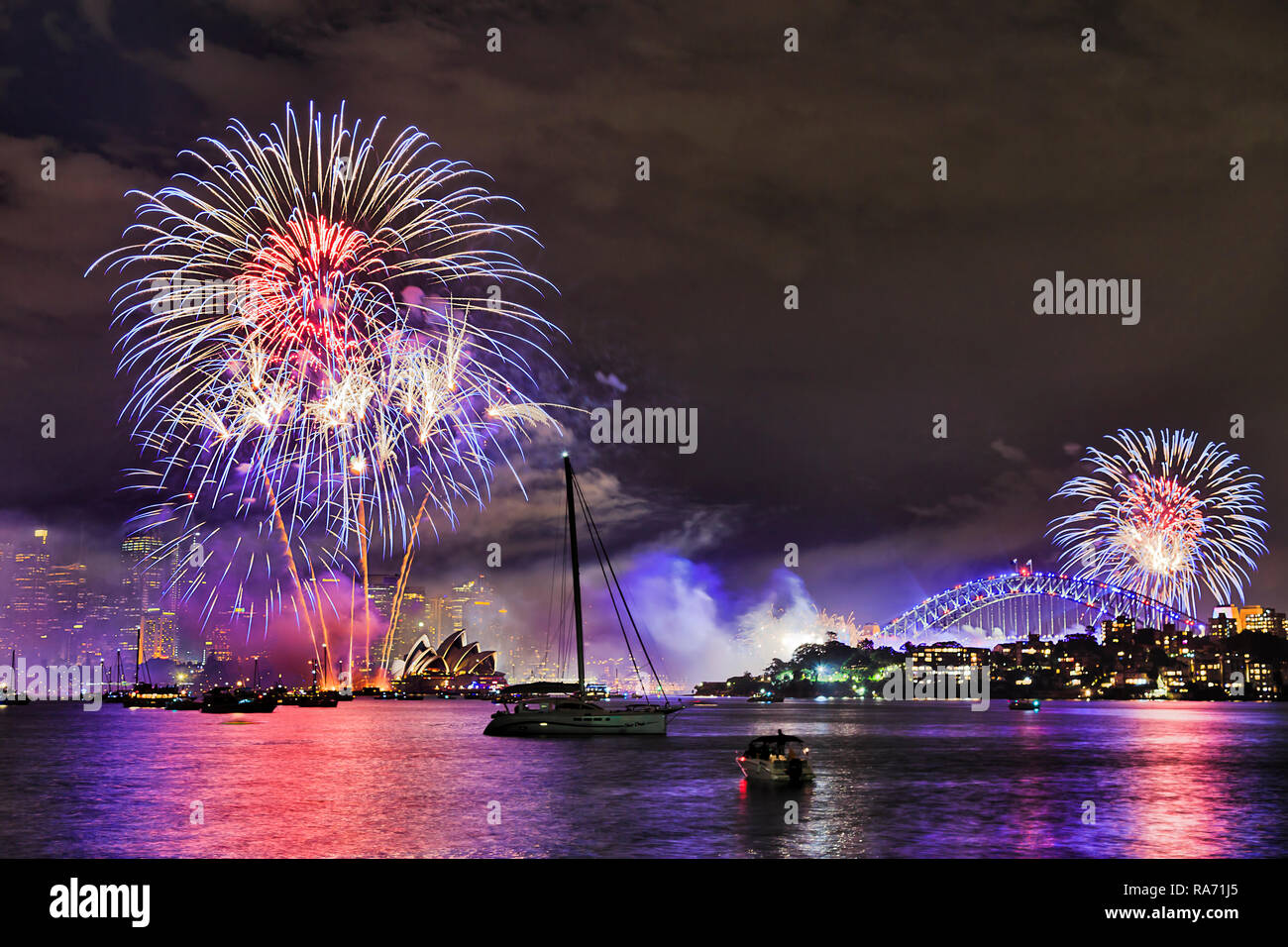 Helles Licht Kugeln der jährlichen Neue Jahr Feuerwerk in Sydney City über CBD Wahrzeichen und in den Gewässern von Sydney Harbour widerspiegelt. Stockfoto