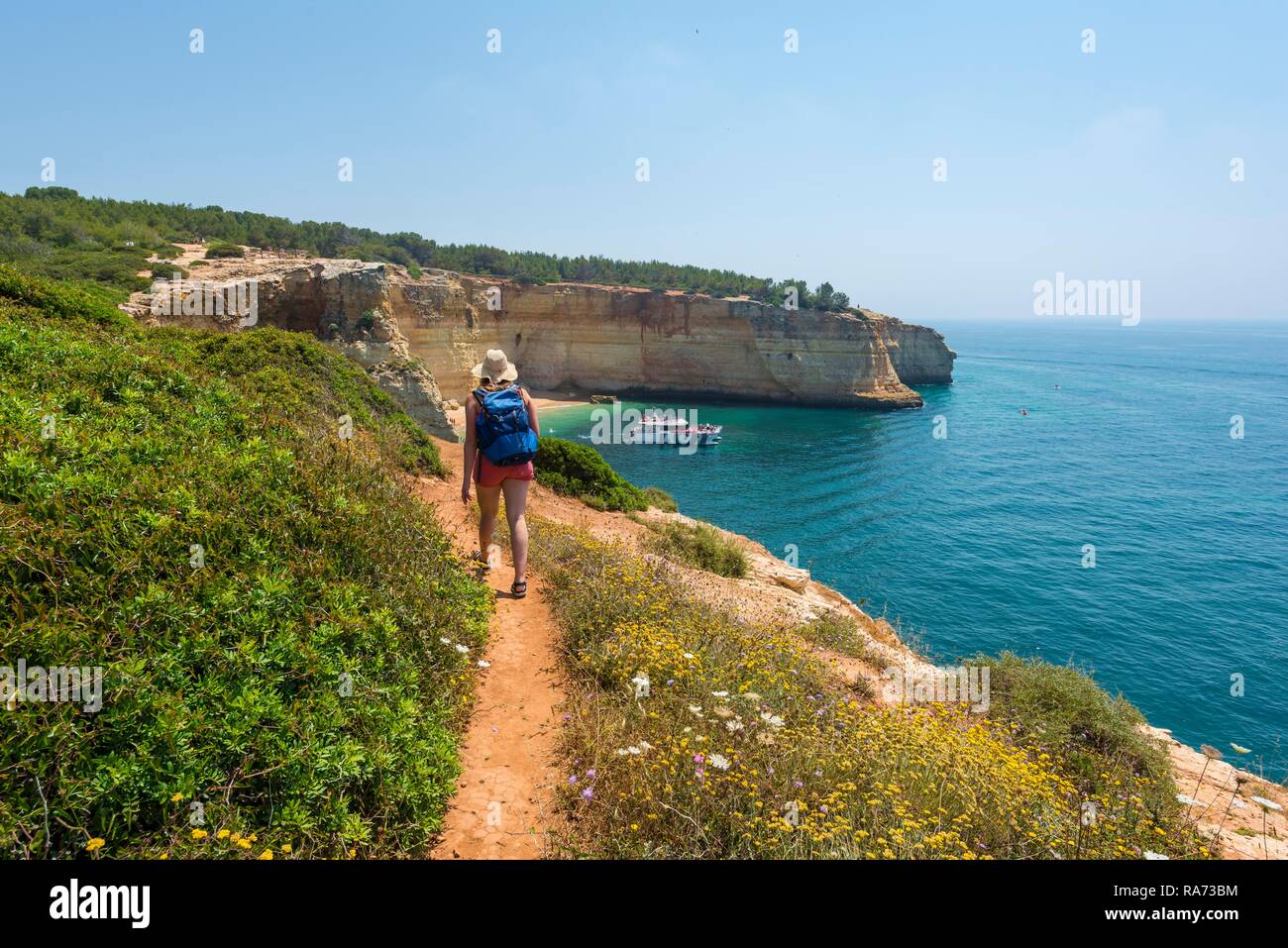 Junge Frau auf einem Wanderweg, mit Blick auf das türkisfarbene Meer, Strand Praia da Marinha, Schroffe Felsenküste von Sandstein Stockfoto