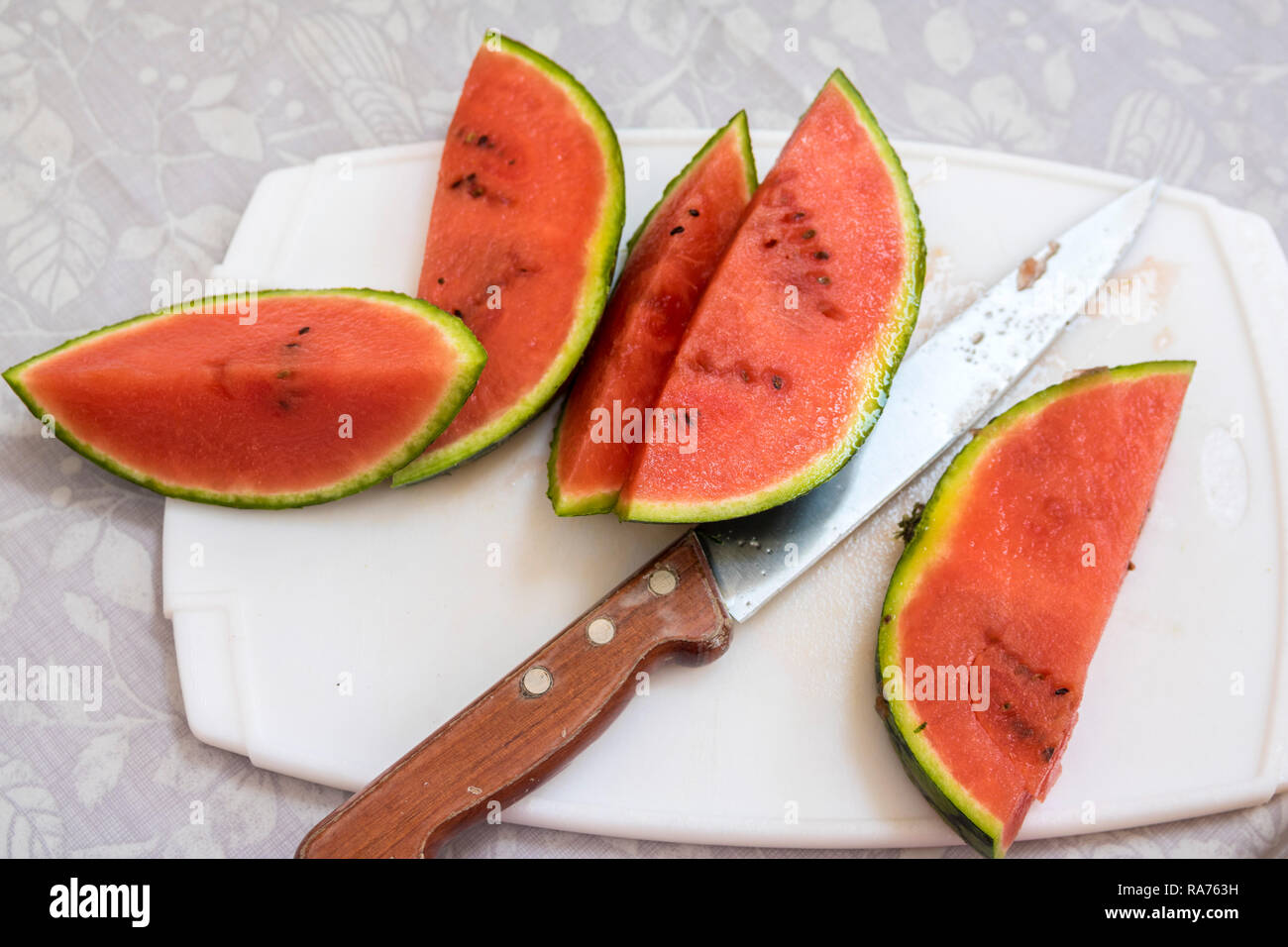 Scheiben rote reife Wassermelone ein Schneidebrett scharfe Schinkenmesser Griff aus Holz, 5 am Tag, gesundes Wohnen, Lifestyle Konzept frisches Obst frühstück Melone Stockfoto