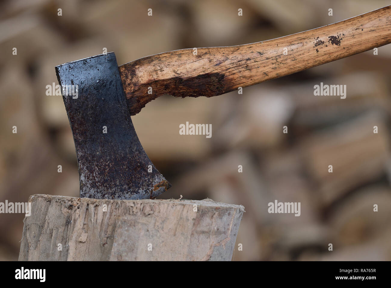 Nahaufnahme eines Ax in einem Block Holz mit einem Stapel von Protokollen im Hintergrund Stockfoto