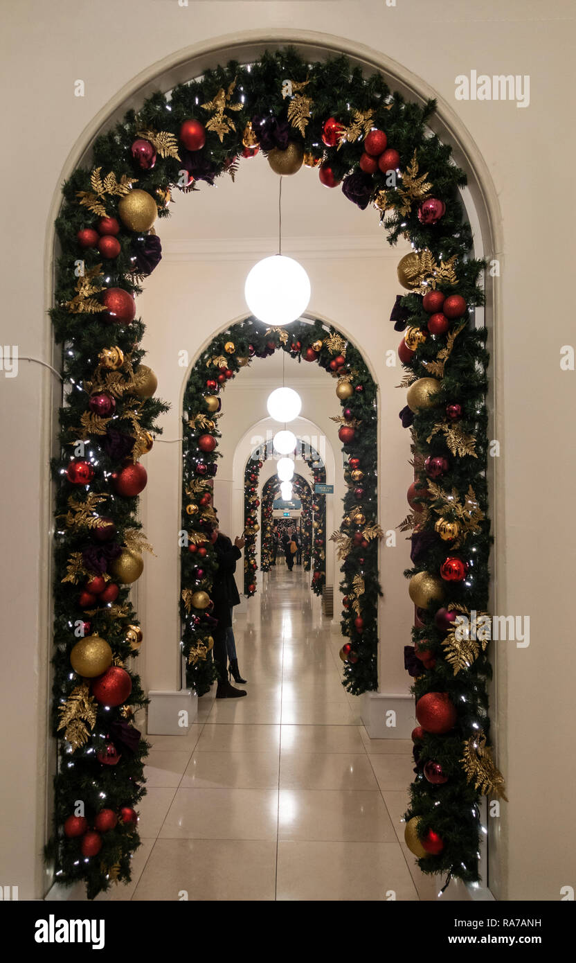 Abnehmende Perspektive zu einer Reihe von Bögen dekoriert mit Weihnachten grün und Dekorationen in grün, gold und rot in Somerset House, central Lond Stockfoto