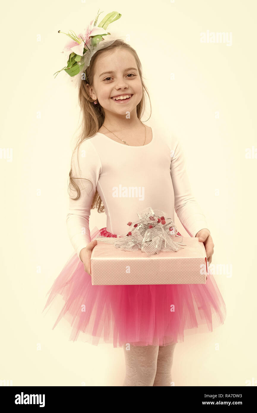 Urlaub, Geburtstag, Jubiläum zu feiern. Kind mit Blume im langen blonden Haare isoliert auf Weiss. Vorhanden oder Geschenk geben. Mädchen ballerina Lächeln mit Box im rosa Tutu Rock. Boxing Day Konzept. Stockfoto