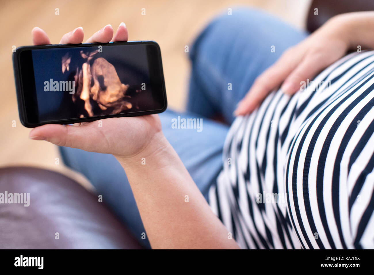 Detail der schwangeren Frau auf der Suche nach 3D-Bild des Babys auf dem Mobiltelefon Stockfoto