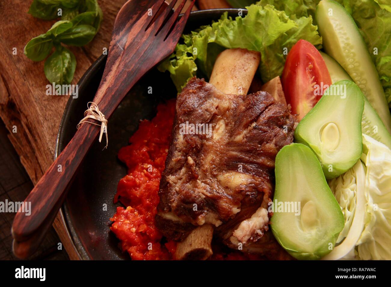 Iga Penyet. Javanisch gebraten - dann - zertrümmerte Rindfleisch Rippen mit roter Chili Paste und frischem Gemüse serviert. Stockfoto