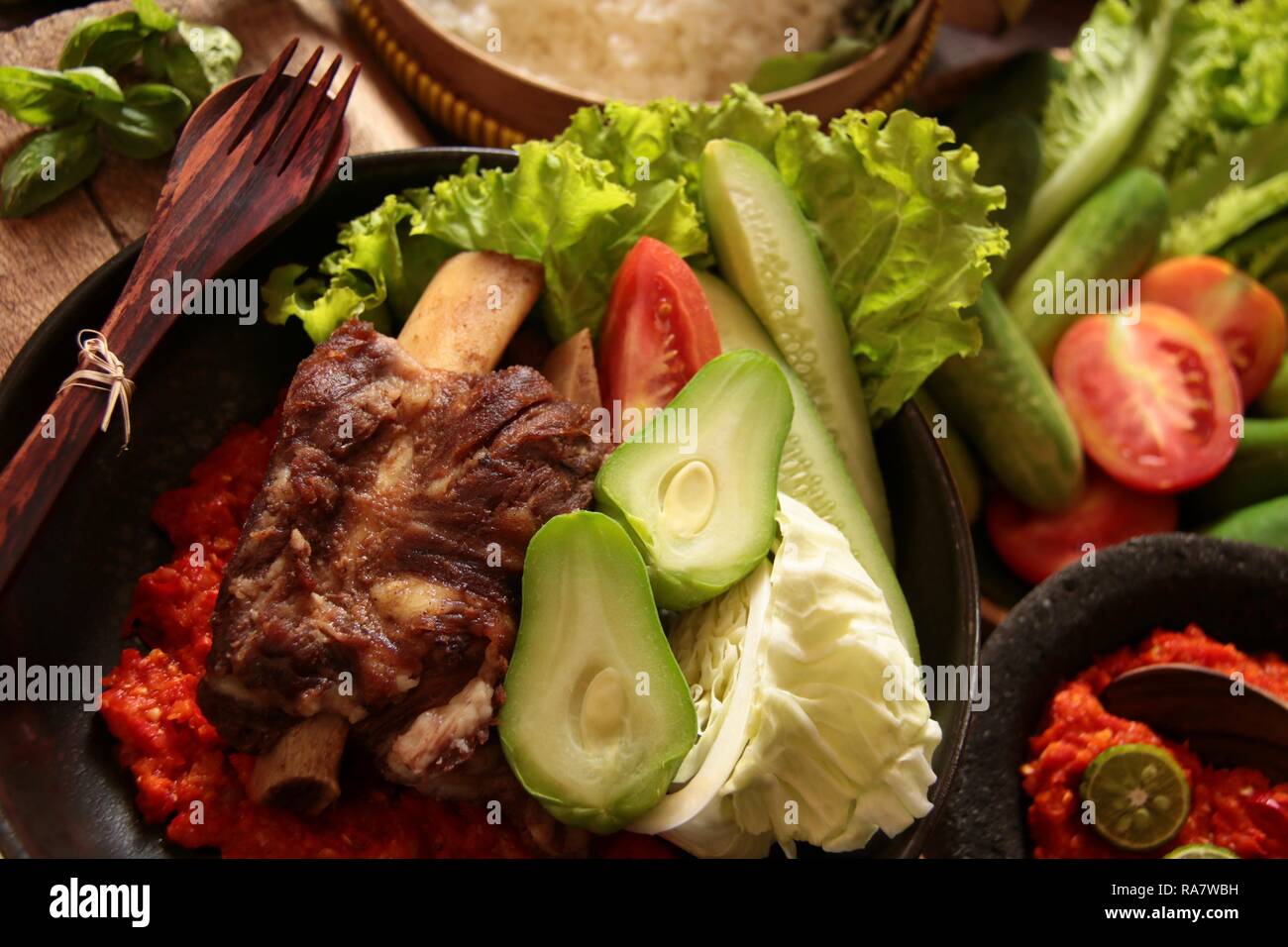 Iga Penyet. Javanisch gebraten - dann - zertrümmerte Rindfleisch Rippen mit roter Chili Paste und frischem Gemüse serviert. Stockfoto
