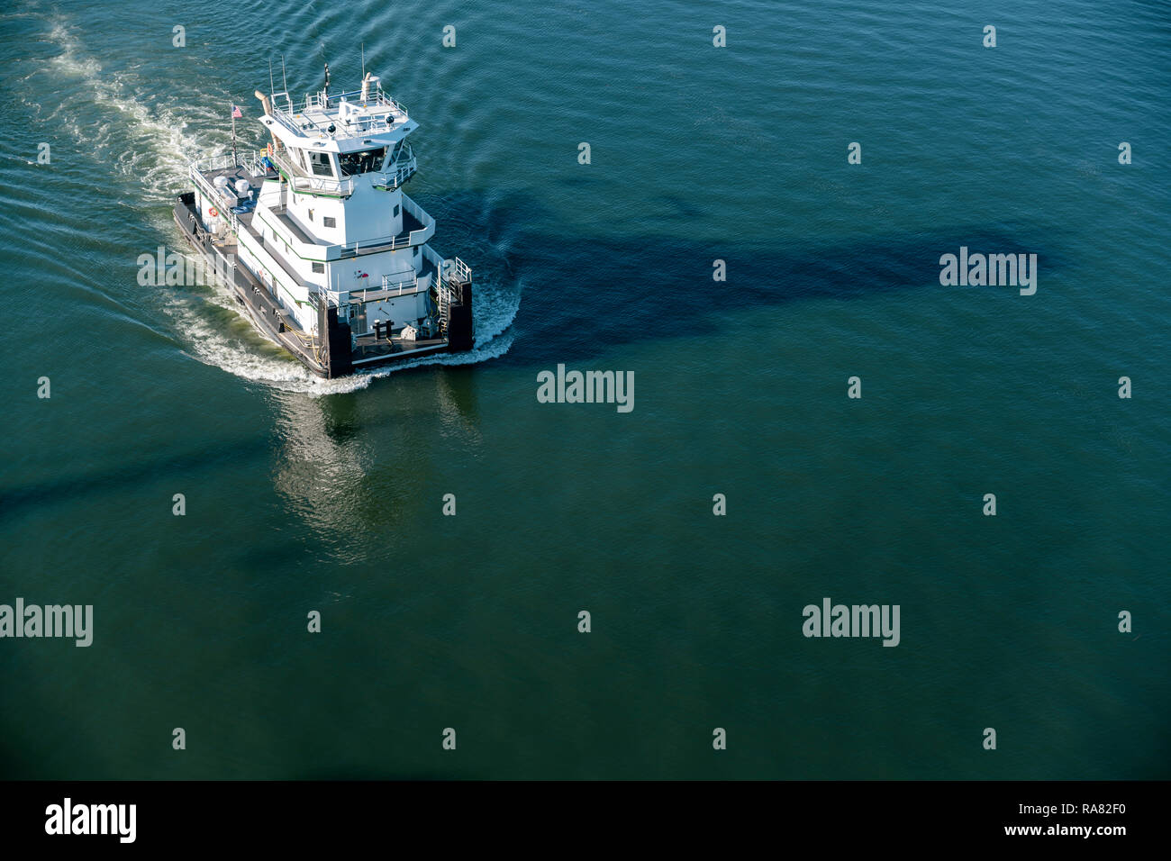 Das prächtige, moderne Schubschiff mit Decks und Kabinen mit Besatzung von Matrosen Schnitte durch die dunklen spiegelglatte Oberfläche des Spiegels ruhigen Wasser verlassen Stockfoto