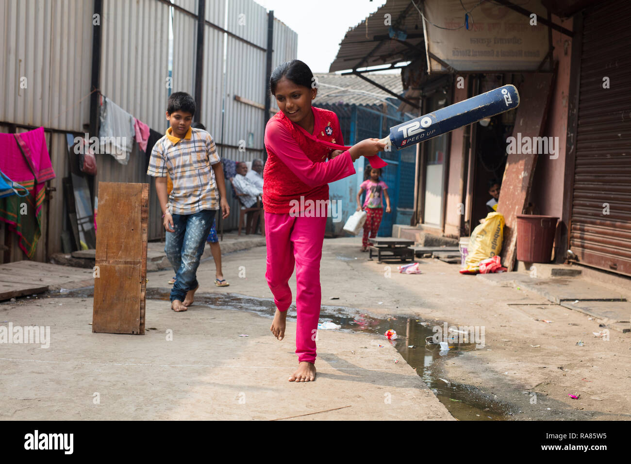 Mumbai, Maharashtra/Indien - 12. Dezember 2017: Kinder spielen so genannte "Gully Cricket' in einer kleinen Straße in einem Slum in Mumbai. Stockfoto