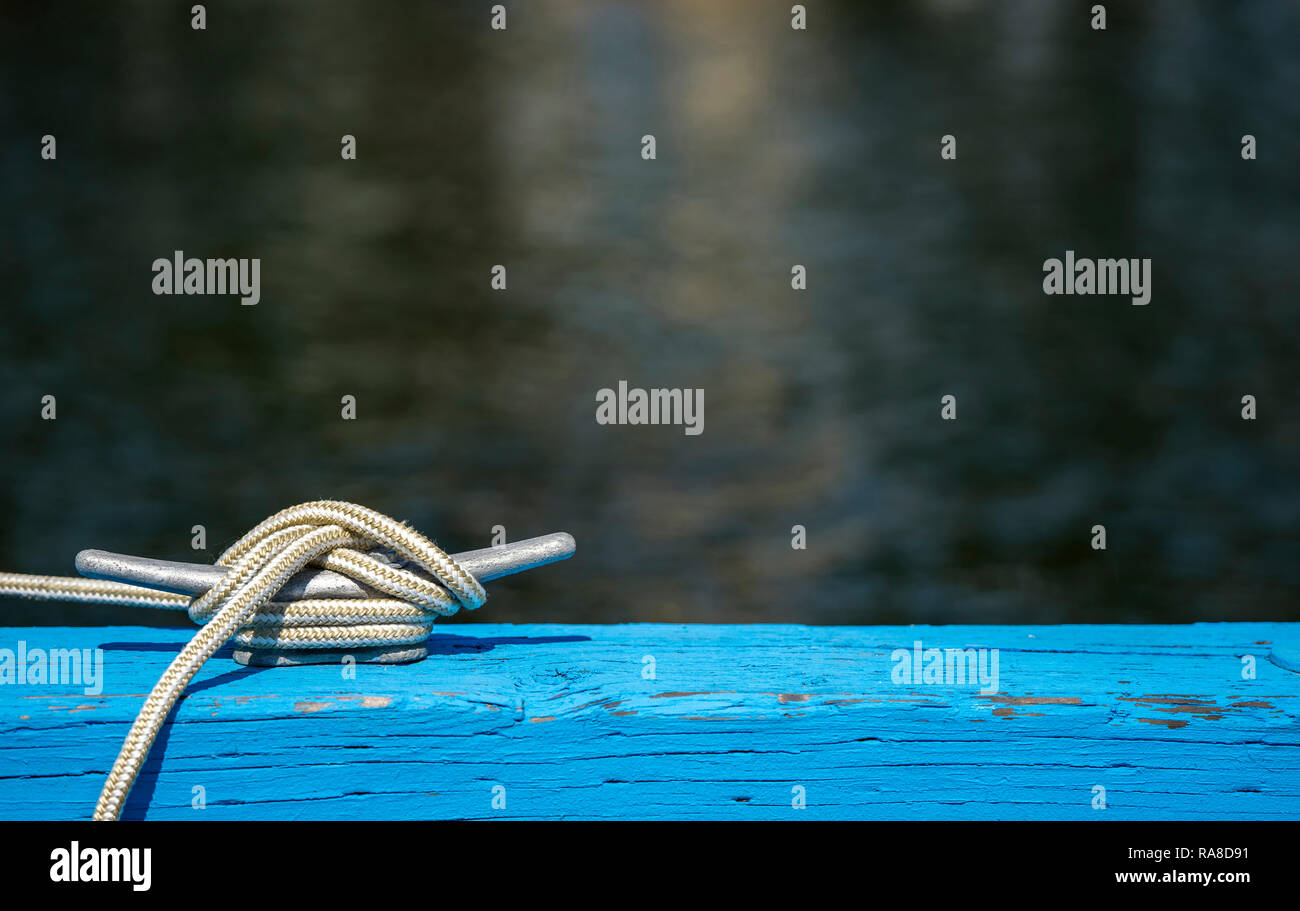 Weiße flexible geflochtener Festmacher Seil vom Boot Seite fest verknotet auf der zuverlässigen starke Metallklammer mit silber Farbe verstärkt am Rande der Blue Stockfoto