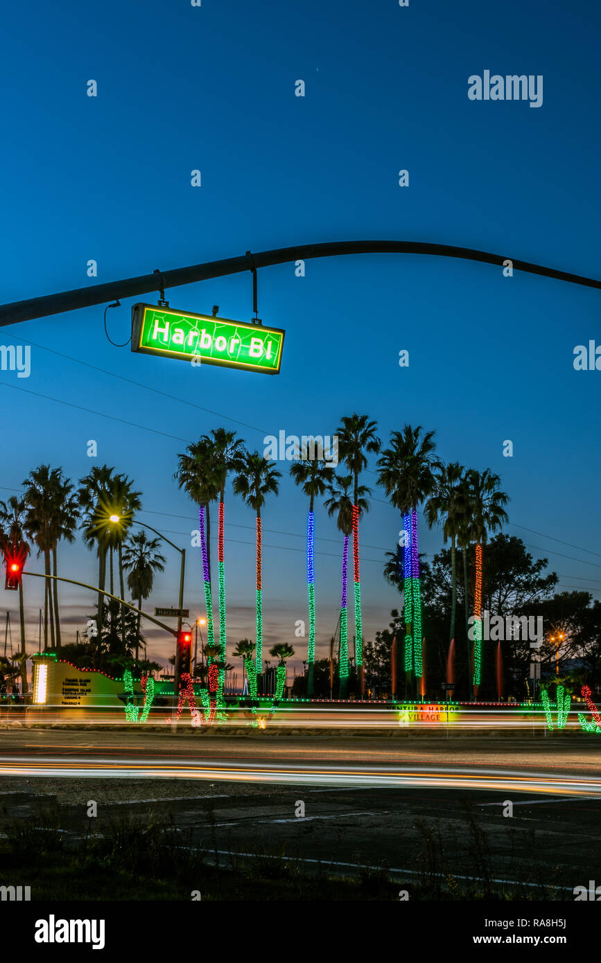 Verkehrsreichen Kreuzung als Sonne hinter Holiday Lights auf Ventura Harbor Bäume am Neujahrstag 2019 in Ventura, Kalifornien, USA. Stockfoto