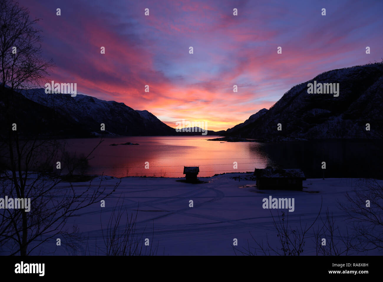 Atemberaubenden Sonnenaufgang über See und Berge mit Hütte Silhouette Stockfoto