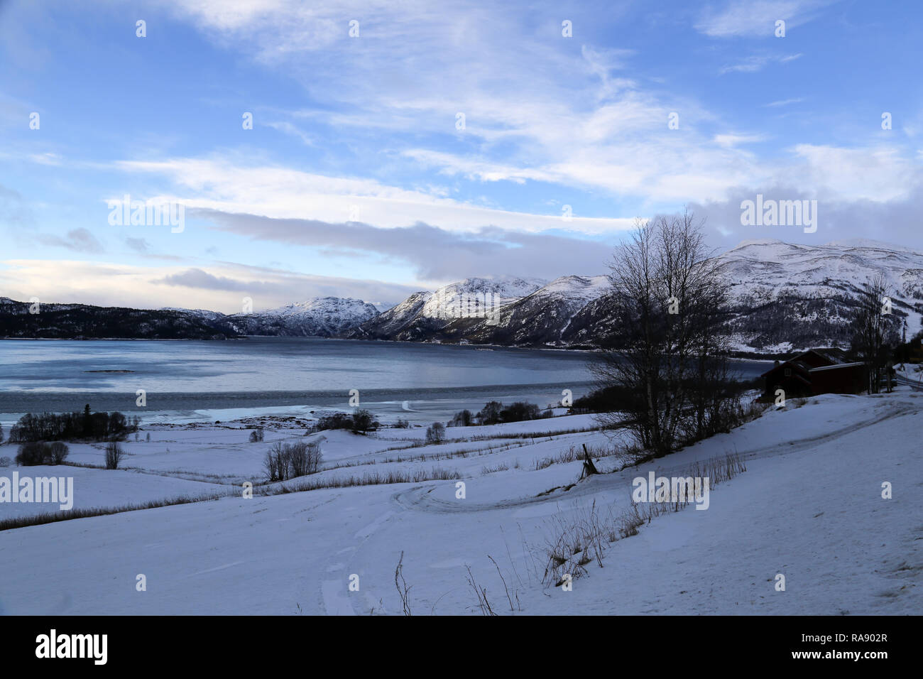 Verschneite Felder mit See und Berge Stockfoto