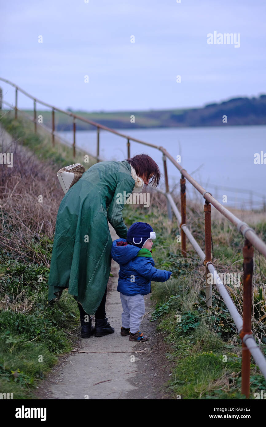 Eine Mutter und ihr Sohn auf einem Pfad, der durch das Meer im Winter in Cornwall, Großbritannien Stockfoto