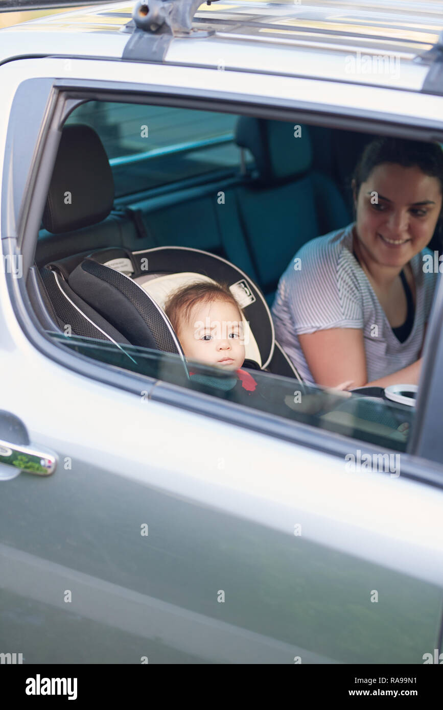Mutter mit einem kleinen Kind auf dem Rücken Autositz der modernen Auto Stockfoto