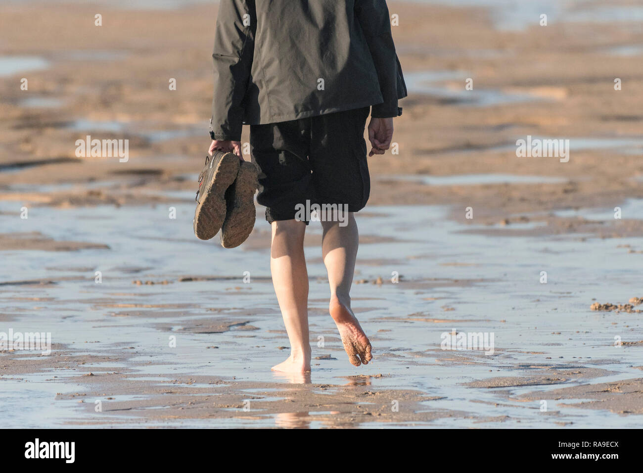 Eine Person zu Fuß am Strand barfuß mit seiner Hose aufgerollt. Stockfoto