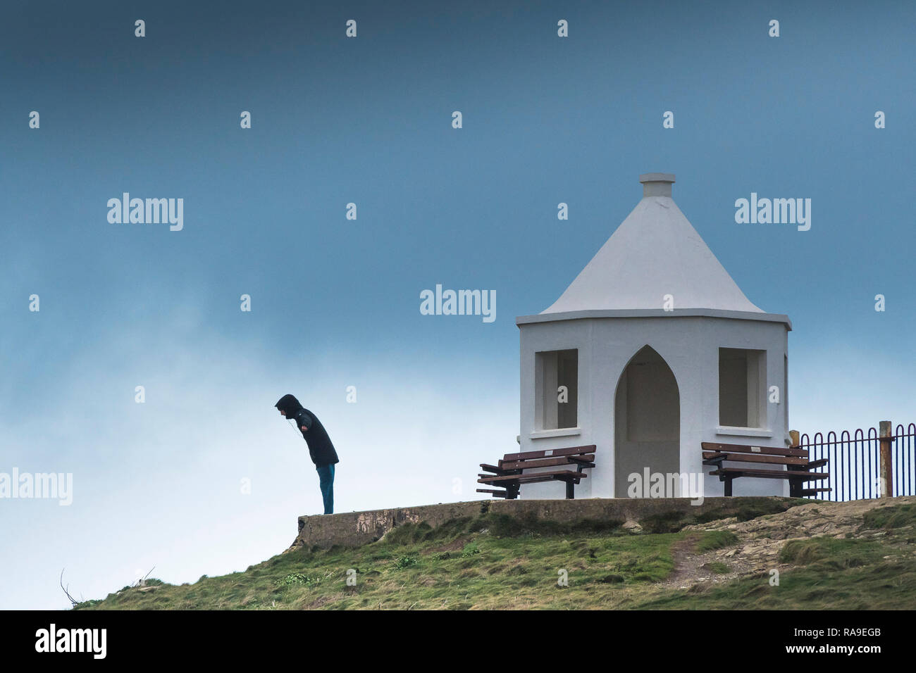 Ein Mann stand neben der alten Küstenwache Lookout Station und lehnte sich in starken Winden auf den Towan Kopf in Newquay in Cornwall. Stockfoto