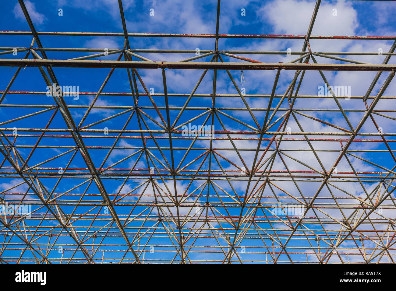 Urban abstrakte Textur Hintergrund. Sicht in blauer Himmel durch alte rostige Geometrische diagonal Metall Konstruktionen von verlassenen Gebäude Stockfoto