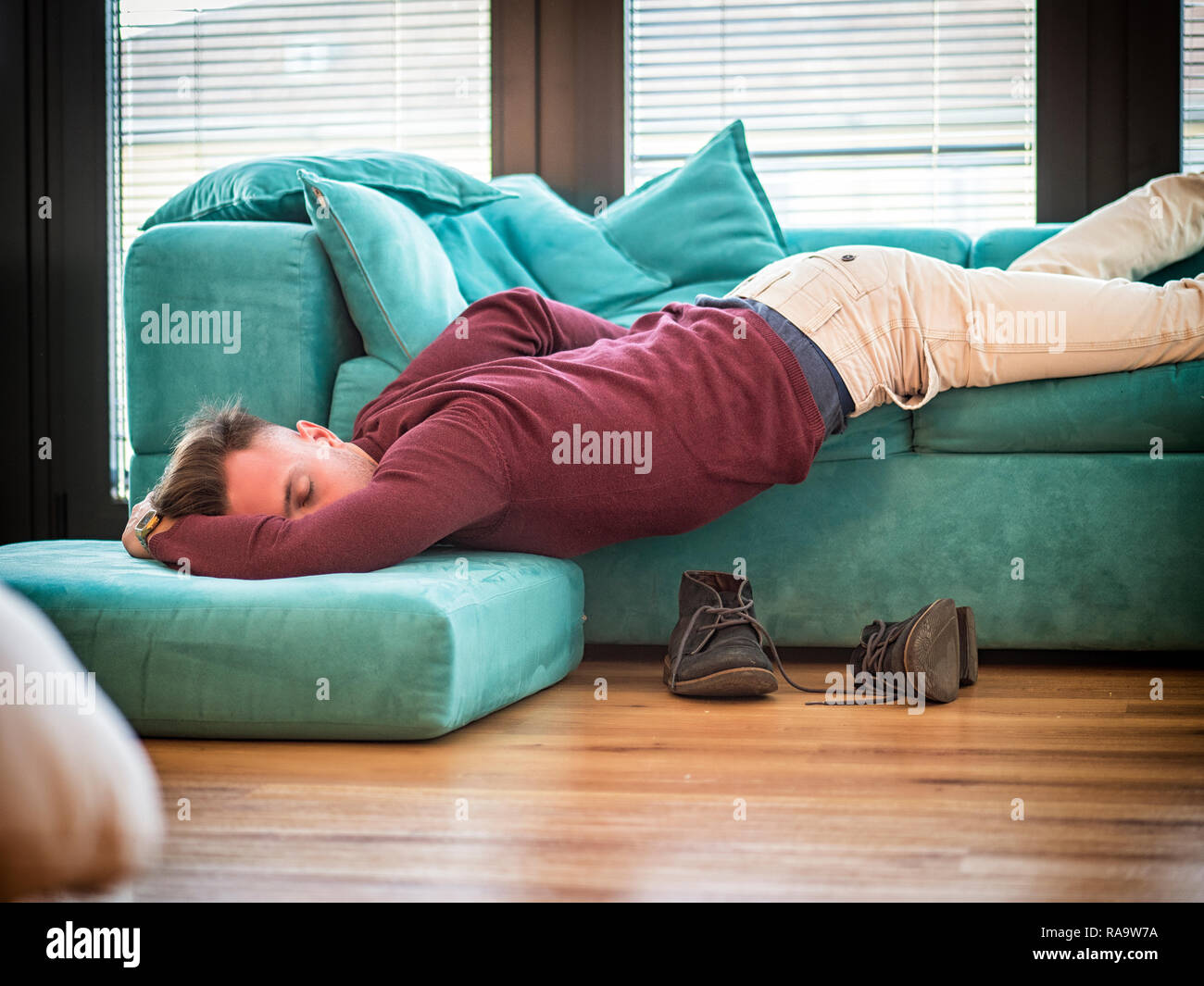 Betrunkener Mann auf der Couch mit dem Kopf auf den Boden Stockfoto