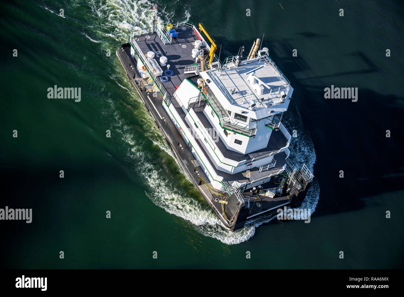 Das prächtige, moderne Schubschiff mit Decks und Kabinen mit Besatzung von Matrosen Schnitte durch die dunklen spiegelglatte Oberfläche des Spiegels ruhigen Wasser verlassen Stockfoto