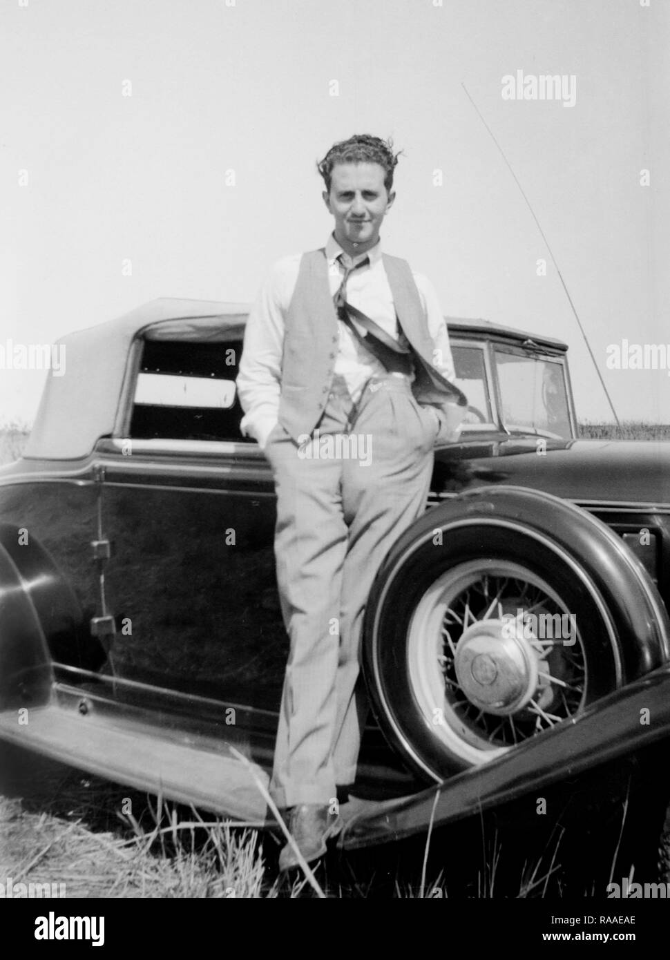 Ein junger Mann stellt auf dem Trittbrett seines Automobils, Ca. 1932. Stockfoto