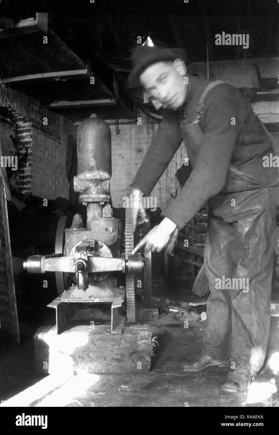 Ein Arbeitnehmer weist darauf hin, seine Werkzeuge in einer Maschinenhalle, Ca. 1925. Stockfoto