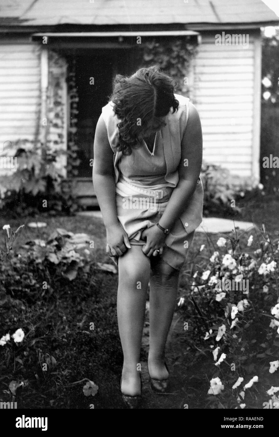 Eine Frau rollt ihre nylons im Garten, Ca. 1930. Stockfoto