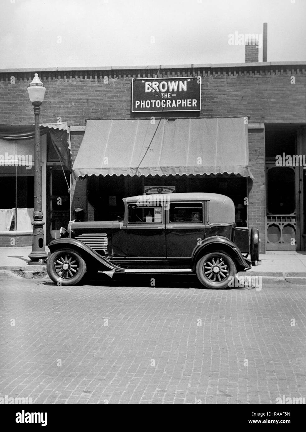 Ein Auto ist auf der Straße vor einem Fotografen studio geparkt, Ca. 1930. Stockfoto
