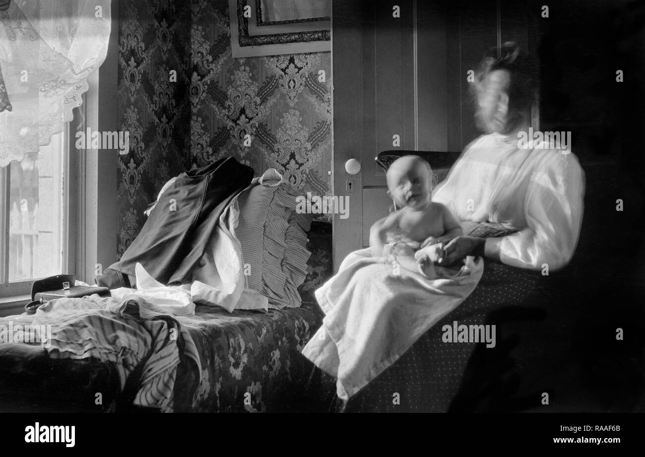 Mutter und Baby sind Unschärfe der Bewegung in einem Schlafzimmer Fenster beleuchtete Szene, Ca. 1915. Stockfoto