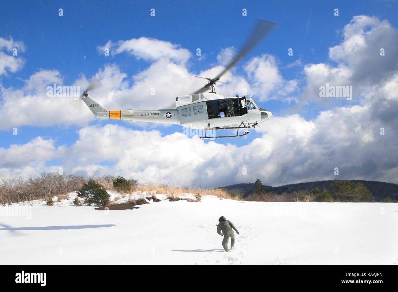 Oberstleutnant Valerie Johnson, 374 medizinische Gruppe Luft- und Raumfahrtmedizin Chief, Spaziergänge in Richtung einer UH-1N Iroquois in das Flugzeug in einer Drop Zone in der Nähe von Mt aufgehoben werden. Fuji, Japan, Jan. 13, 2017. Das bordpersonal abgeschlossen Hebezeug einsetzen und Extraktion aus dem Hubschrauber von 25-35 Meter über dem Boden. Stockfoto