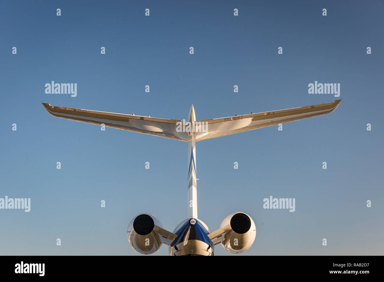 Schwanz eines persönlichen Business Jet Flugzeug leuchtet durch die warme Sonne vor blauem Himmel, symmetrisch Stockfoto