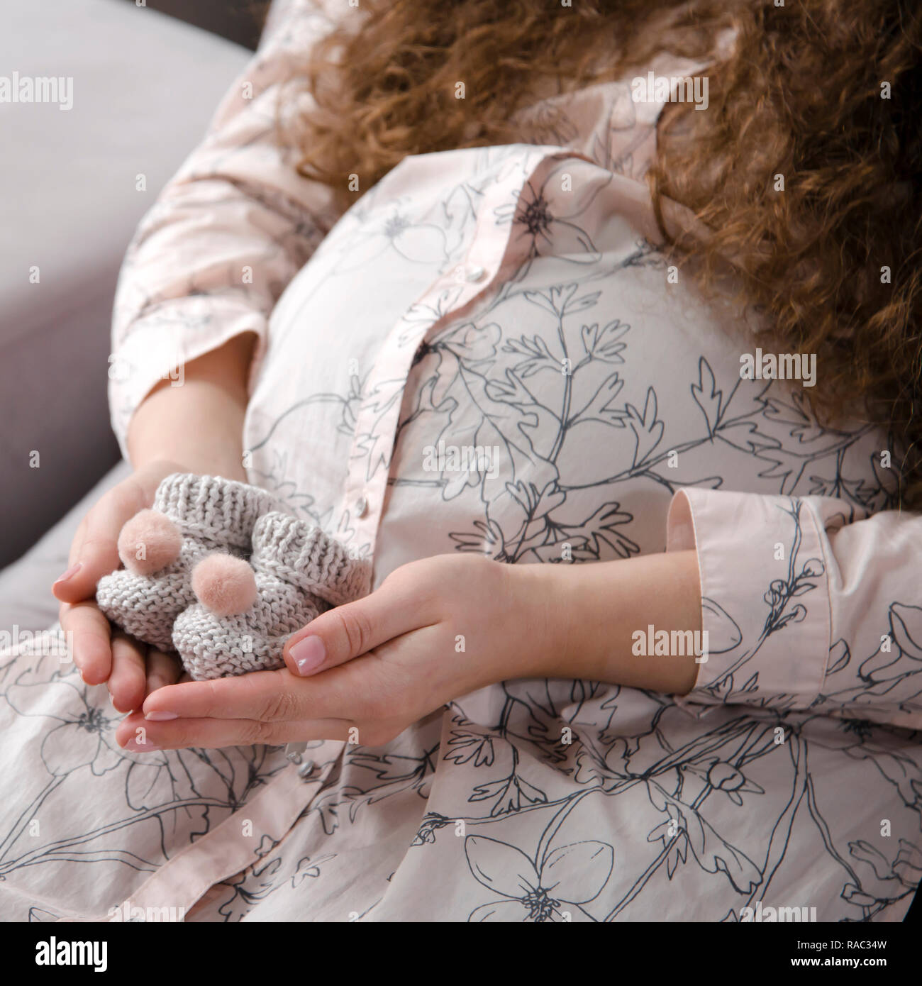 Die jungen zukünftigen Mutter - eine Schwangere sanfte Frau mit einer gerundeten Bauch bereitet sich auf die Geburt des Kindes und hält in ihrer Hände kleine aus Gewirken aus Wolle Stockfoto