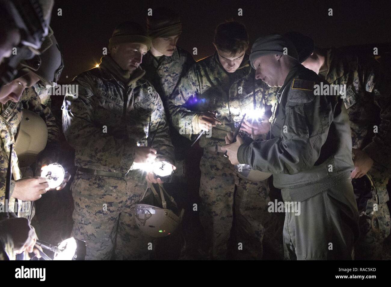 1 Leutnant John Adams, rechts, 36th Airlift Squadron C-130 Hercules Navigator, zeigt Marines aus dem 3 Reconnaissance Bataillon, 3rd Marine Division, III Marine Expeditionary Force wie Drop Zone Anzeige leuchtet bei Yokota Air Base, Japan, Jan. 11, 2017, während der Woche Springen zu betreiben. III MEF Marines durchgeführt weeklong springen Ausbildung von einem US Air Force C-130H, zu den 36 als zugewiesen. Die Ausbildung nicht nur erlaubt, die Marines zu springen üben, aber es ist auch erlaubt, die yokota Besatzungen Flug Taktik und Zeit zum Üben - Paket fällt. Stockfoto